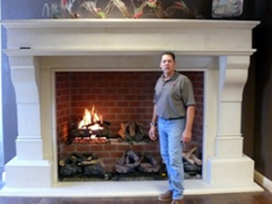 A man standing next to a fireplace created by Pacific Hearth & Home, Inc. in Rancho Cordova, CA
